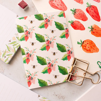 greeting cards with strawberry and floral patterns on a light surface