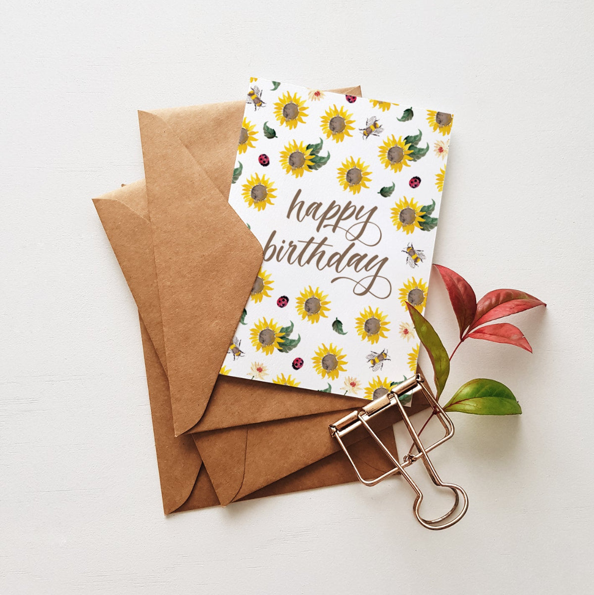 Happy birthday with sunflowers on a stack of brown envelopes near stationery