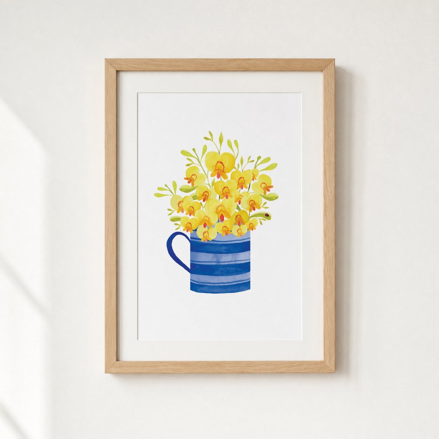 Framed artwork of a blue mug with yellow flowers on a white background