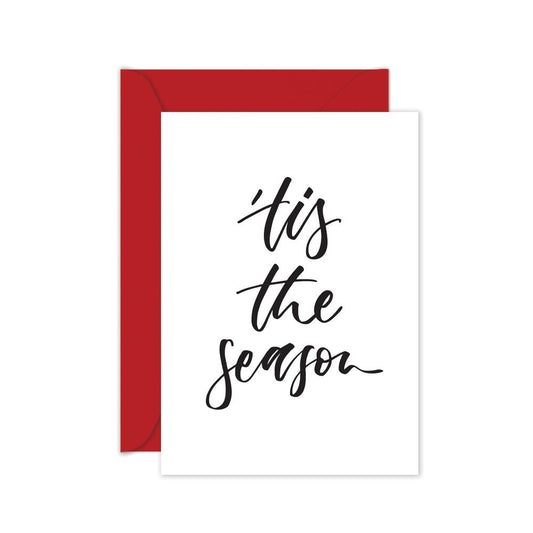 Christmas card with black script 'tis the season' on a red envelope