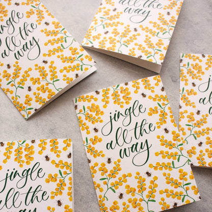 Set of greeting cards with 'jingle all the way' text and floral design on a grey surface