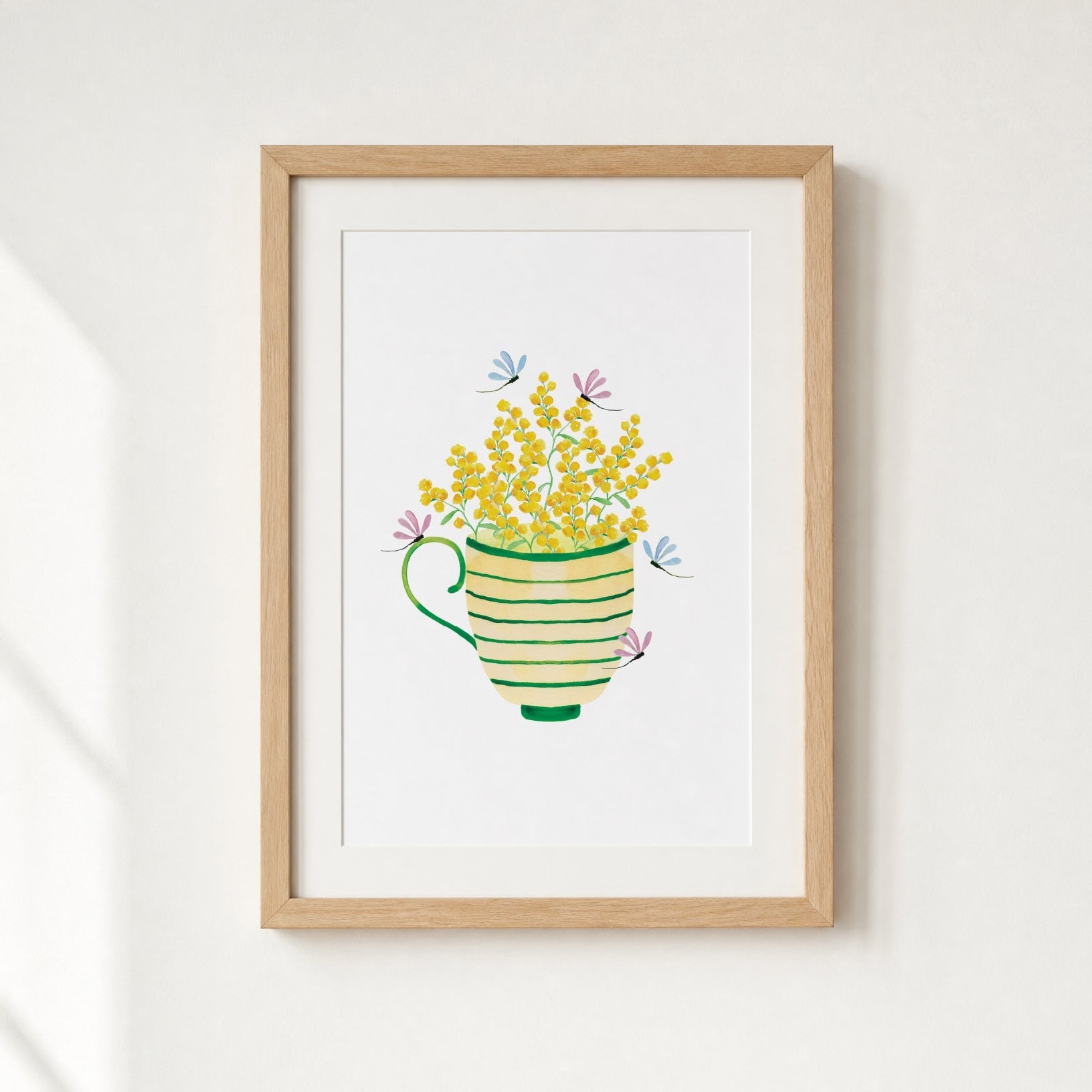 Framed artwork of a teacup with yellow flowers on a white wall