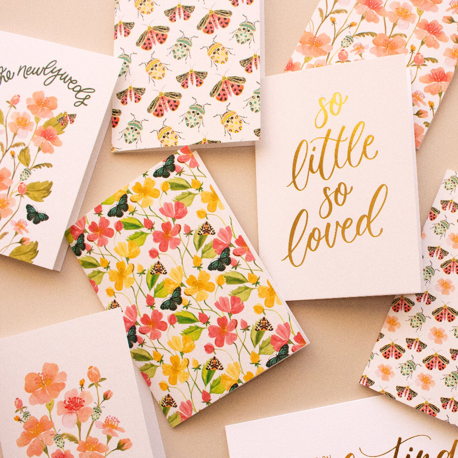 Collection of various greeting cards with floral designs and text on a beige background