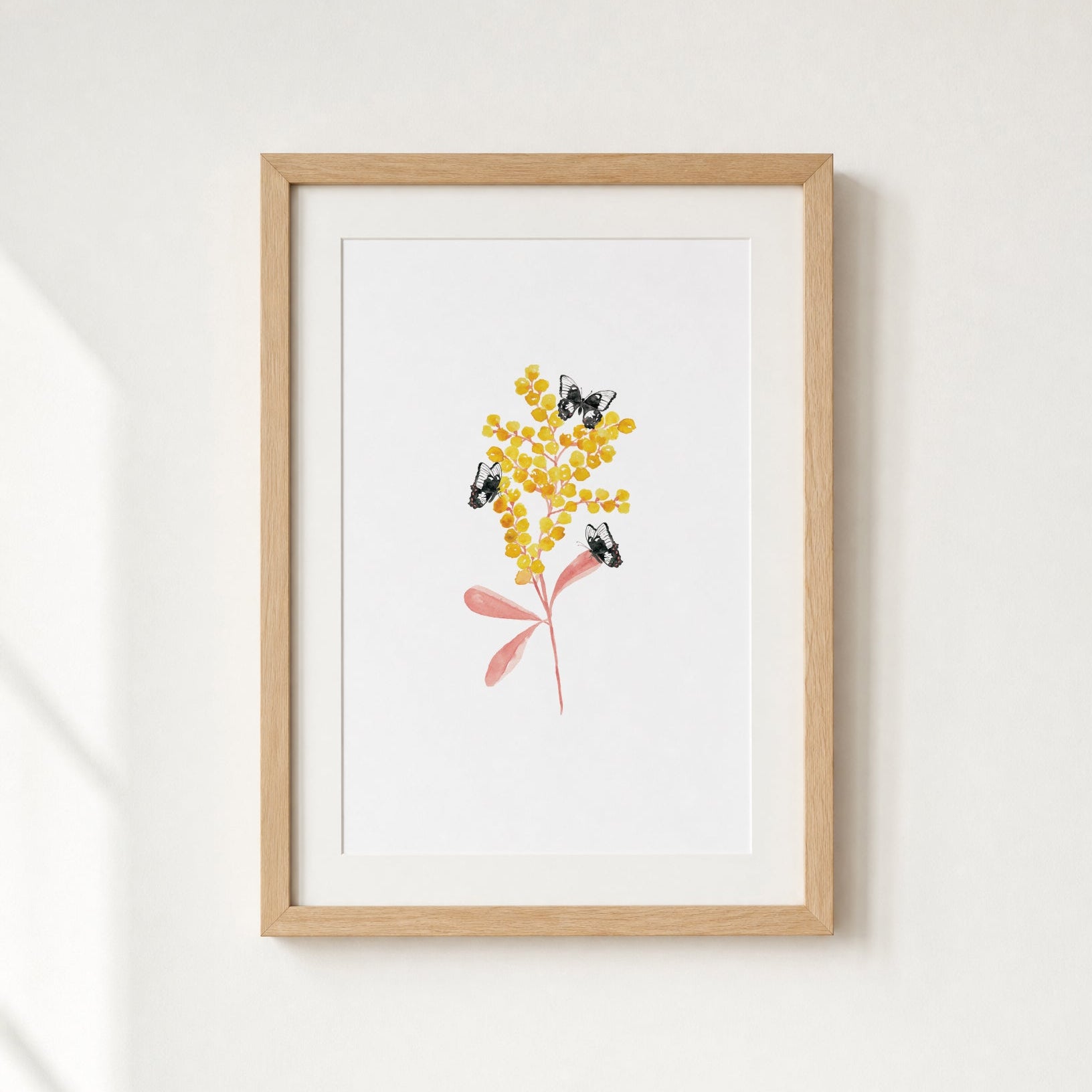 Framed artwork of a bouquet of yellow flowers with a pink leaves on a white wall.