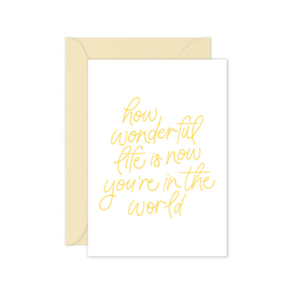 Greeting card with yellow text saying 'how wonderful life is now you're in the world' on a white background, cream envelope.