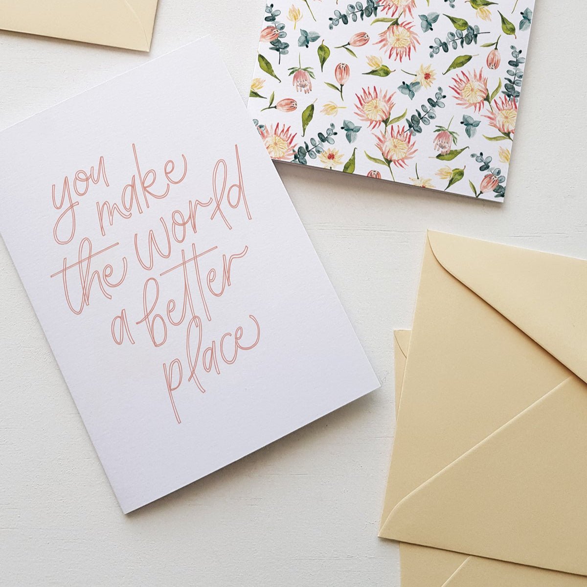 Floral card and card with 'you make the world a better place' text on a light background