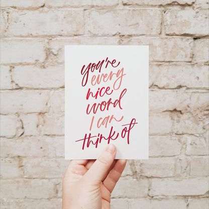 Hand holding a card with red text against a brick wall