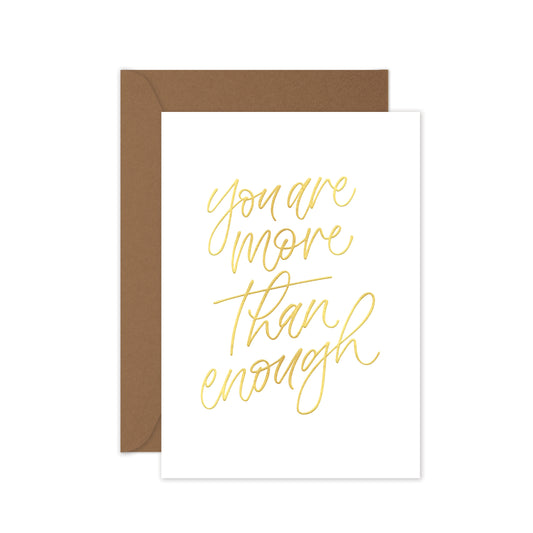 Greeting card with wrods 'You are more than enough' in gold foil, brown envelope on a white background