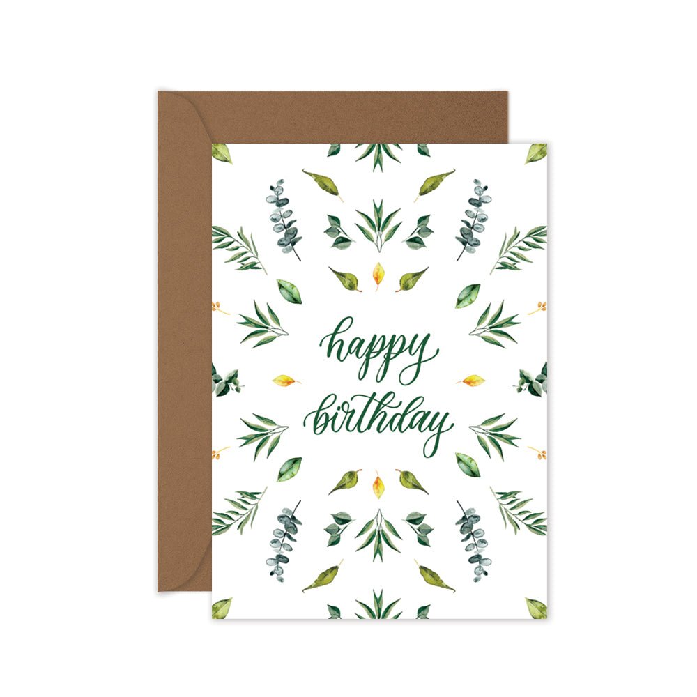 A botanical inspired birthday card with green and yellow leaves pattern and the words 'happy birthday' in the center, and a brown kraft envelope.
