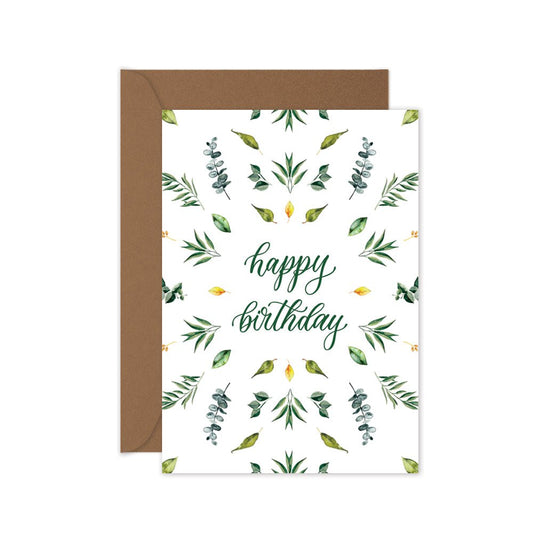 A botanical inspired birthday card with green and yellow leaves pattern and the words 'happy birthday' in the center, and a brown kraft envelope.